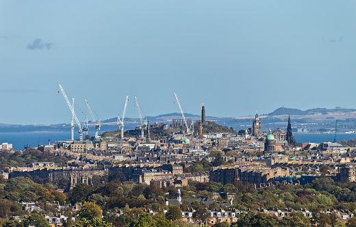 A cityscape photograph of Edinburgh showing Calton Hill, the National Records of Scotland and the Firth of Forth.