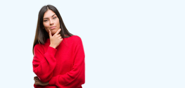 istock Young beautiful hispanic wearing red sweater looking confident at the camera with smile with crossed arms and hand raised on chin. Thinking positive. 1043291902