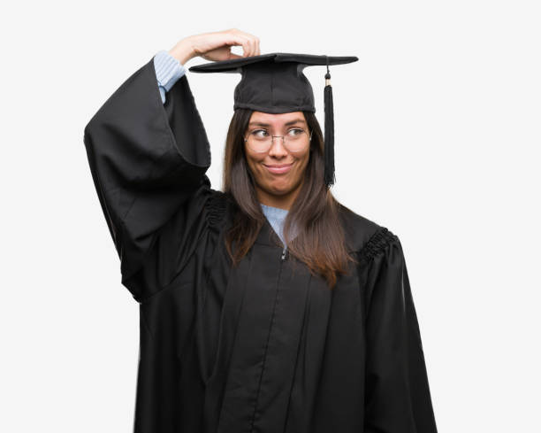 Young hispanic woman wearing graduated cap and uniform confuse and wonder about question. Uncertain with doubt, thinking with hand on head. Pensive concept.