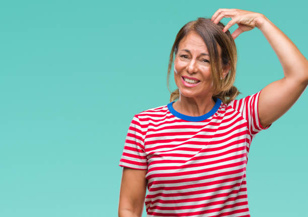 Middle age senior hispanic woman over isolated background confuse and wonder about question. Uncertain with doubt, thinking with hand on head. Pensive concept.