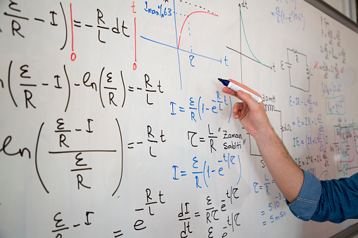 Young student studying physics formula in front of the whiteboard