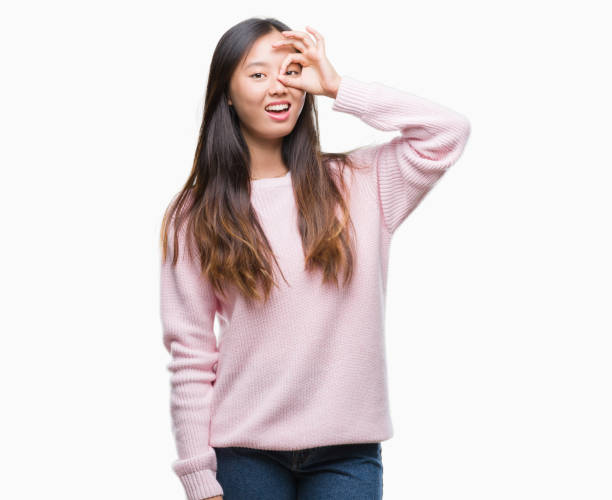 istock Young asian woman over isolated background doing ok gesture with hand smiling, eye looking through fingers with happy face. 1043299528