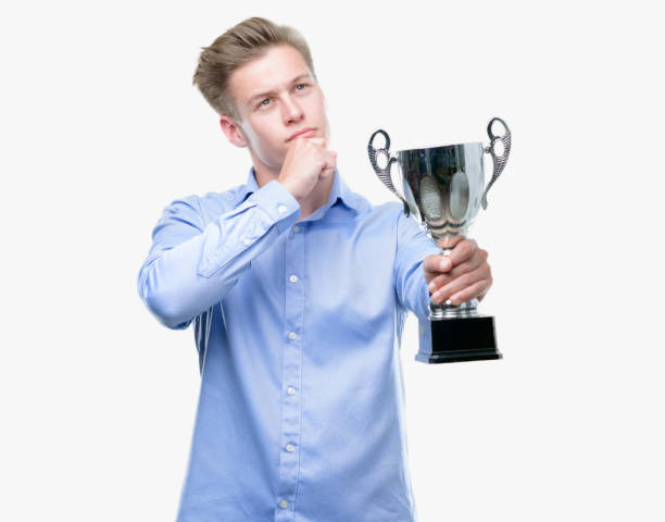 istock Young handsome blond man holding a trophy serious face thinking about question, very confused idea 1043302926