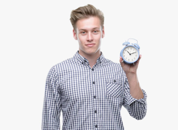 istock Young handsome blond man holding alarm clock with a confident expression on smart face thinking serious 1043303304