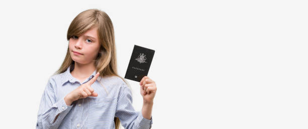 młoda blondynka malucha trzymającego australijski paszport bardzo szczęśliwy wskazując z ręką i palcem na bok - man made object vacations children only side view zdjęcia i obrazy z banku zdjęć