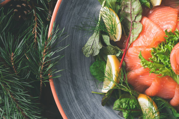 A traditional Swedish Christmas dinner with gravlax on a wooden table. Decorated with pine needles and candles.