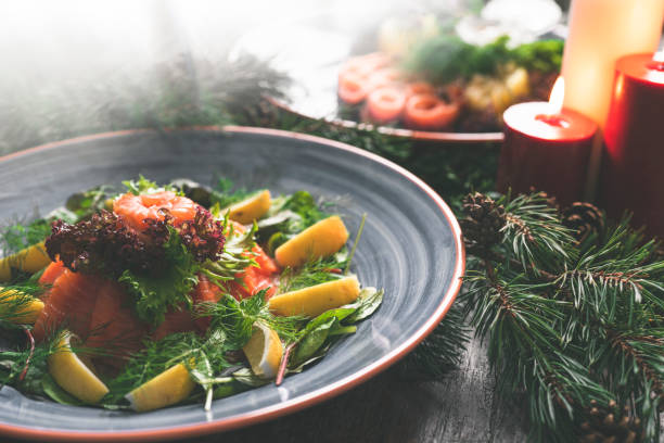 A traditional Swedish Christmas dinner with gravlax on a wooden table. Decorated with pine needles and candles.