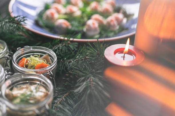 A traditional Swedish Christmas dinner with pickled herring in sauce on a wooden table. Decorated with pine needles and candles.
