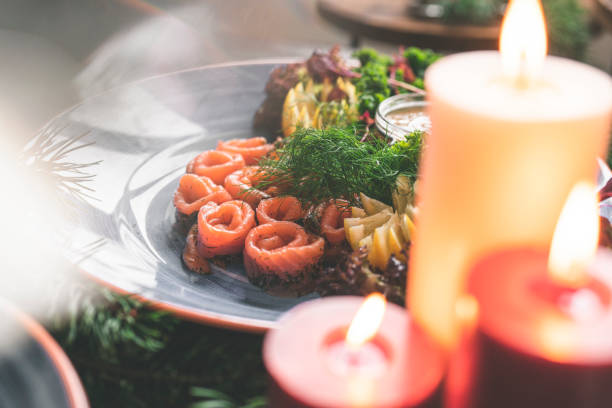 A traditional Swedish Christmas dinner with gravlax on a wooden table. Decorated with pine needles and candles.