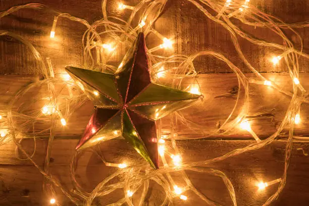 Christmas star ornament shot with christmas lights on vintage wooden background