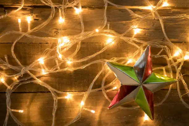 Christmas star ornament shot with christmas lights on vintage wooden background