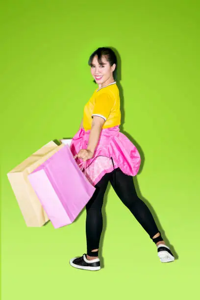 Portrait of pretty girl smiling at the camera while carrying shopping bags. Shot with green screen