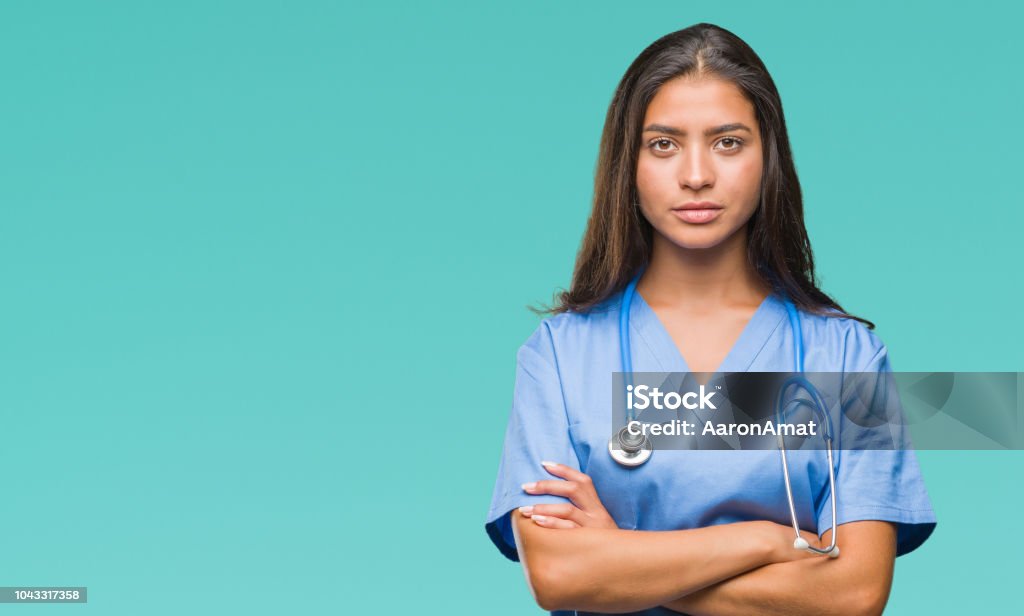 Young arab doctor surgeon woman over isolated background skeptic and nervous, disapproving expression on face with crossed arms. Negative person. Serious Stock Photo