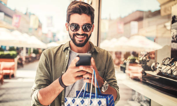 Shopping time. Modern young man with shopping bags making a phone call. Consumerism, shopping, lifestyle concept Man in shopping. Smiling man with shopping bags enjoying in shopping. Consumerism, shopping, lifestyle concept shopping photos stock pictures, royalty-free photos & images