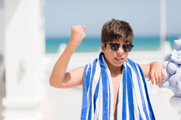 niño de vacaciones lleva una toalla azul marino junto a la playa molestada y frustrado gritando con furia, loca y gritar con mano levantada, concepto de ira - furious blue little boys caucasian fotografías e imágenes de stock