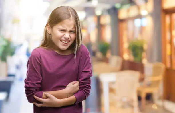 Young beautiful girl over isolated background with hand on stomach because indigestion, painful illness feeling unwell. Ache concept.