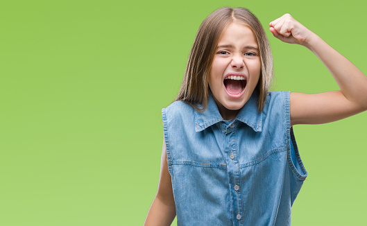 Young beautiful girl over isolated background angry and mad raising fist frustrated and furious while shouting with anger. Rage and aggressive concept.