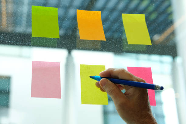 istock hand write on adhesive notes on glass wall. Sticky note paper reminder schedule for discussing creative idea & business brainstorming 1043341076