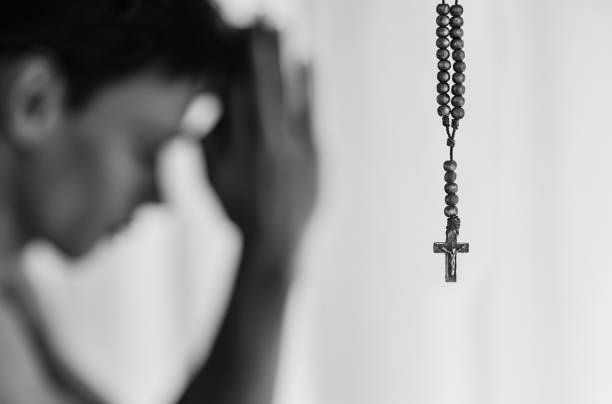 nahaufnahme des rosenkranzes mit mann, der betet im hintergrund - confession booth penance catholicism church stock-fotos und bilder