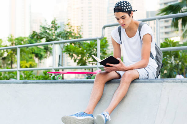 istock Young man reading at the skateboard park. 1043341472