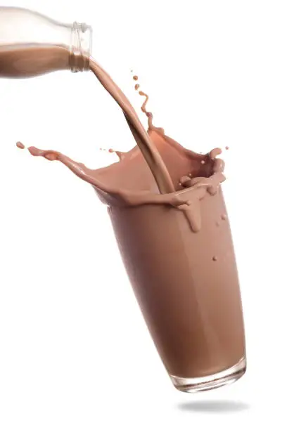 Pouring chocolate milk from bottle into glass with splashing isolated on white background.