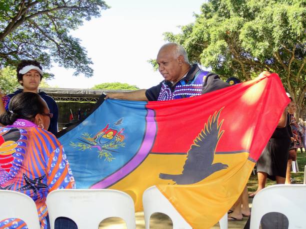 enfoque en aborígenes australianos familia sosteniendo y mirando la bandera aborigen - palm island fotografías e imágenes de stock