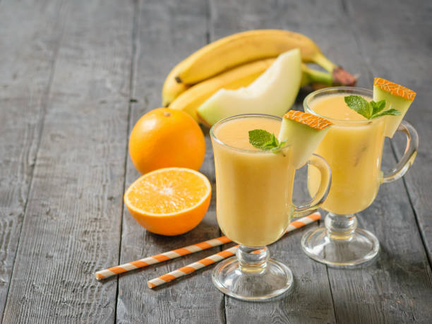 istock Two glass mugs with melon smoothie and a half melon on a gray table. 1043403680