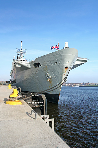 The main mast of HMAS Canberra, a Canberra Class Amphibious Assault Ship of the Royal Australian Navy, is surrounded by scaffolding.  She is docked at Garden Island naval base in Sydney Harbour.   This image was taken on a sunny afternoon on 11 November 2023.