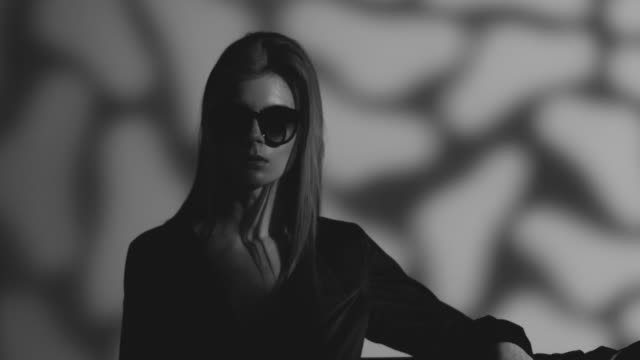 High fashion blond model in sunglasses dressed black moves. Fashion video. Black and white. Slow Motion. 4K 30fps ProRes 4444