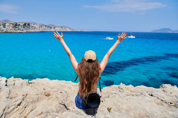Rear View Of Woman Standing At Beach Against Sky Italian vacations series. Rear View Of Woman Standing At Beach Against Sky formentera island stock pictures, royalty-free photos & images