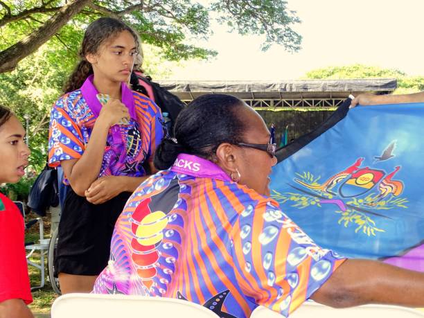 z bliska australijskiej kobiety aborygenów i dwóch młodych aborygenów patrząc na aborygeńskiej flagi. - australia aborigine group of people friendship zdjęcia i obrazy z banku zdjęć