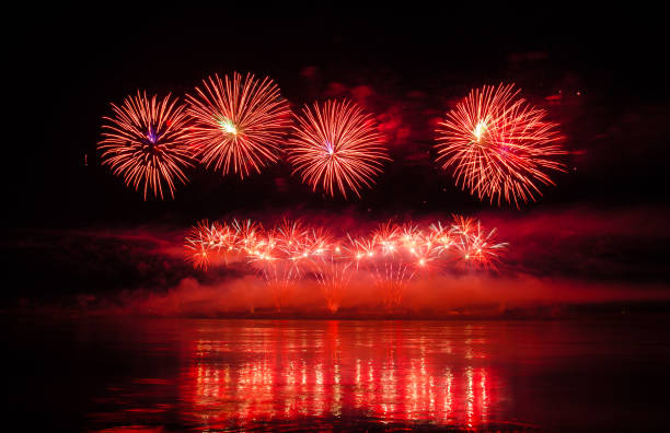 beautiful colorful holiday fireworks with reflections in the water on the black sky background, close-up, long exposure - independence spark fire flame imagens e fotografias de stock