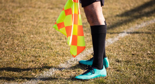istock Soccer referee assistant stands at sideline with flag at hands. Blur green field background, close up. 1043437684