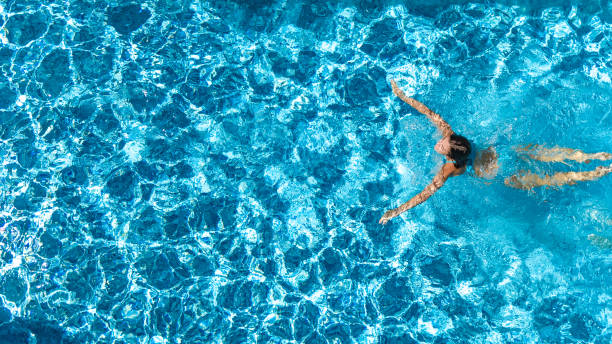 luftbild-drohne blick auf aktive mädchen im schwimmbad von oben, yong frau schwimmt im blauwasser, tropischen urlaub, urlaub am resort-konzept - swimmingpool stock-fotos und bilder