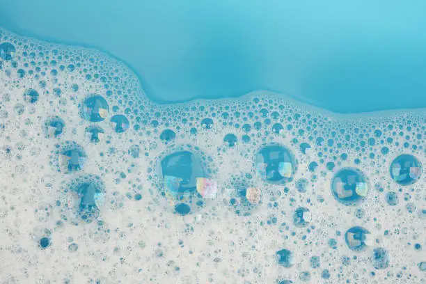 Bubble foam on blue water surface background top view