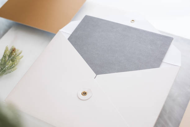 istock top perspective view of blank grey card in white envelop with pine leaf on two layer step of marble table top.Mock up template for display of design,modern business items. 1043444252