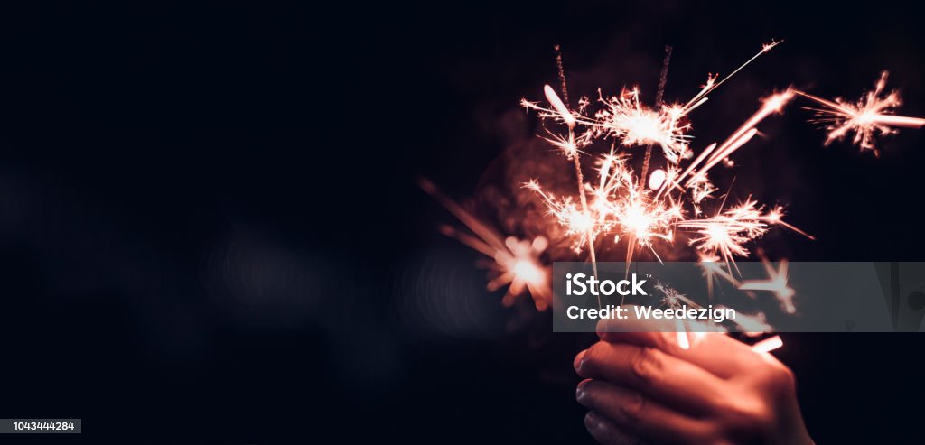 Hand holding burning Sparkler blast on a black bokeh background at night,holiday celebration event party,dark vintage tone Sparkler - Firework Stock Photo