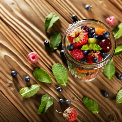 Top view of assorted fruits in mason jar on kitchen wooden table
