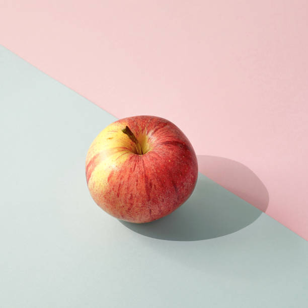istock fresh ripe apple on colored paper background 1043465734