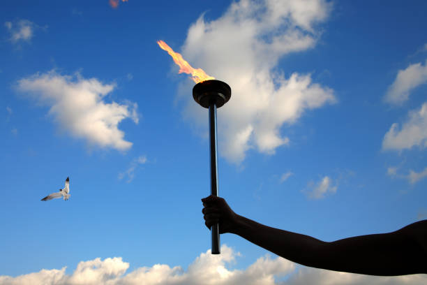istock Close up hand holding burning flaming torch over cloudy sky 1043471158