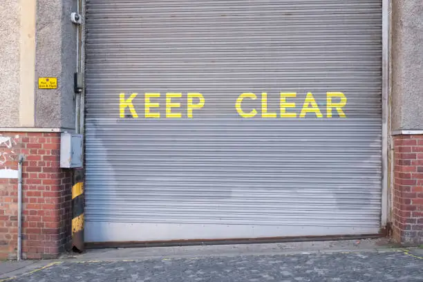 Keep clear sign on roller shutter door large yellow text  uk