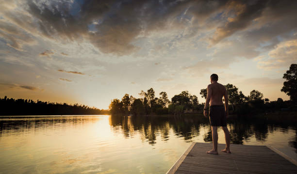istock Young man standing without shirt looking at the sunset 1043476990