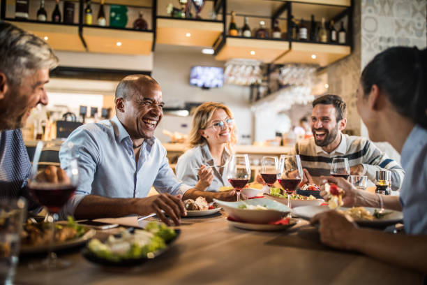 Group of cheerful business people having fun on a lunch. Cheerful business colleagues talking about something funny on a lunch break in a restaurant. business lunch stock pictures, royalty-free photos & images