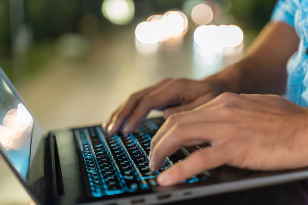 istock Male hands typing on laptop keyboard outdoors at night 1043483688