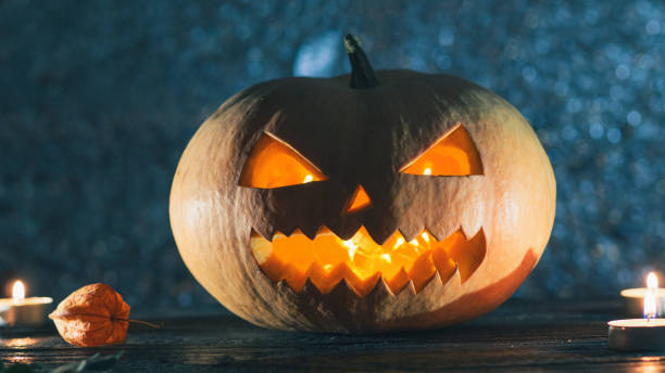 istock Cool pumpkin killer on Halloween in smoke on dark background with candles 1043487656