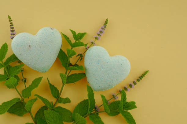 istock Mint bath bombs. Organic cosmetics with mint extract. bath bombs in heart form with mint extract and twigs of fresh mint on a yellow background. 1043494638