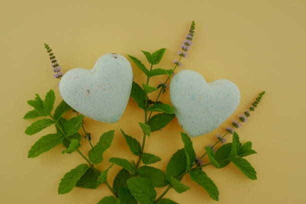 istock Mint bath bombs. body cosmetics with mint extract. bath bombs in heart form with mint extract and twigs of fresh mint on a yellow background. 1043494654