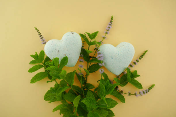 istock Mint bath bombs.Organic body cosmetics with mint extract. bath bombs in heart form with mint extract and twigs of fresh mint on a yellow background. 1043494660