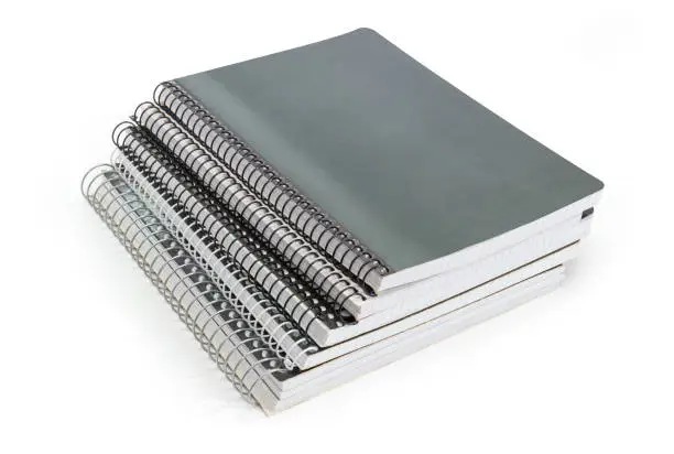Stack of the different exercise books with wire spiral binding on a white background