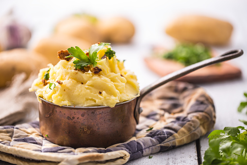 Mashed potatoes in old panl decorated parsley herbs and roasted bacon pieces.